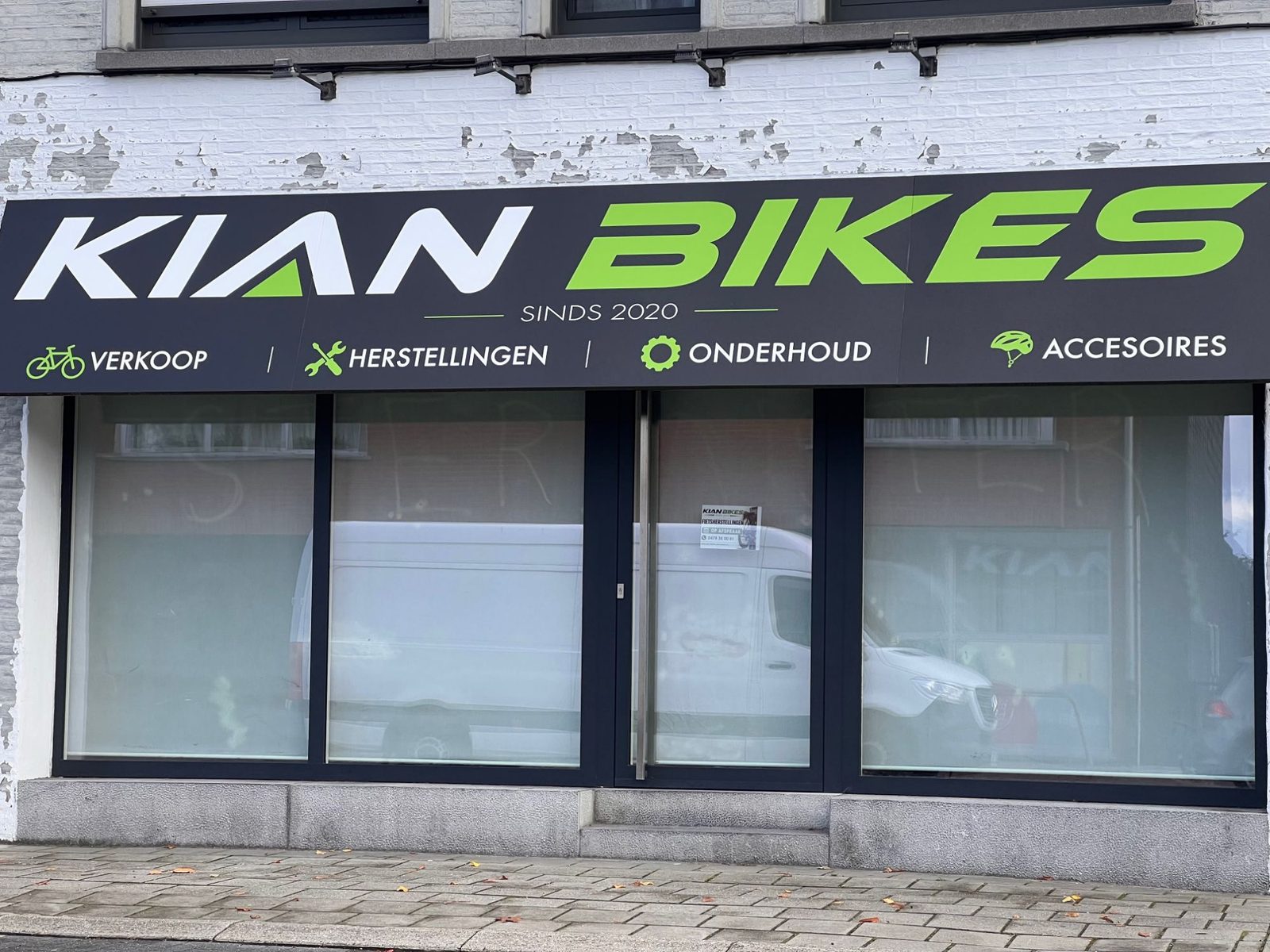 Gevel van Kian Bikes in Brecht met het zwart-groene uithangbord: verkoop, herstellingen, onderhoud en accessoires